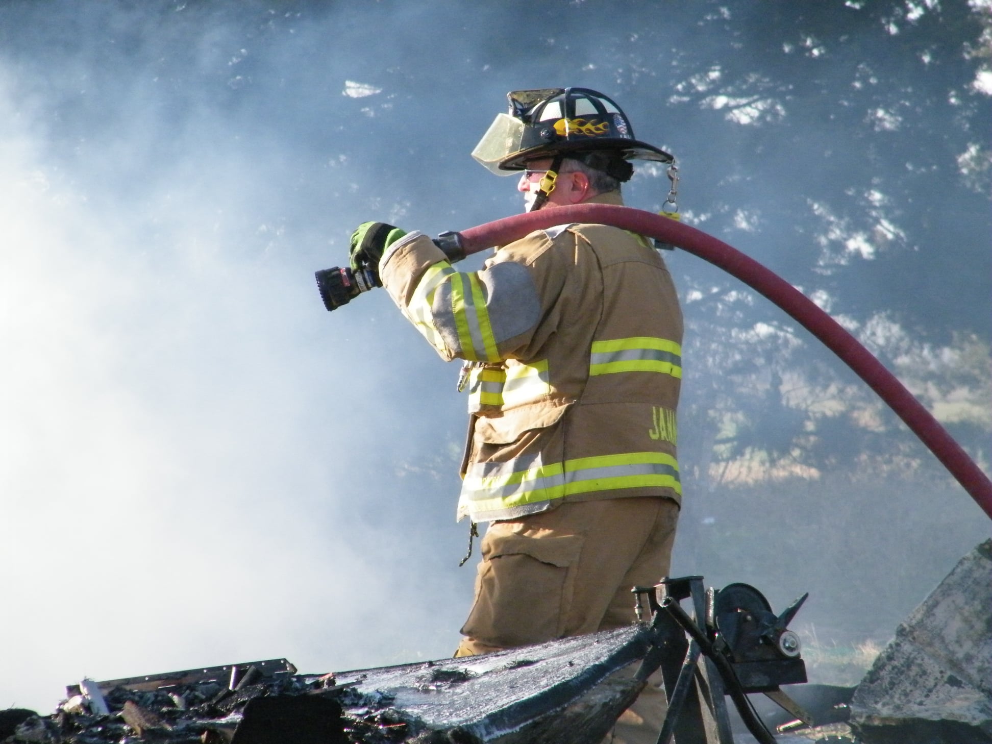 Firefighter Standing In Smoke, Holding A Hose